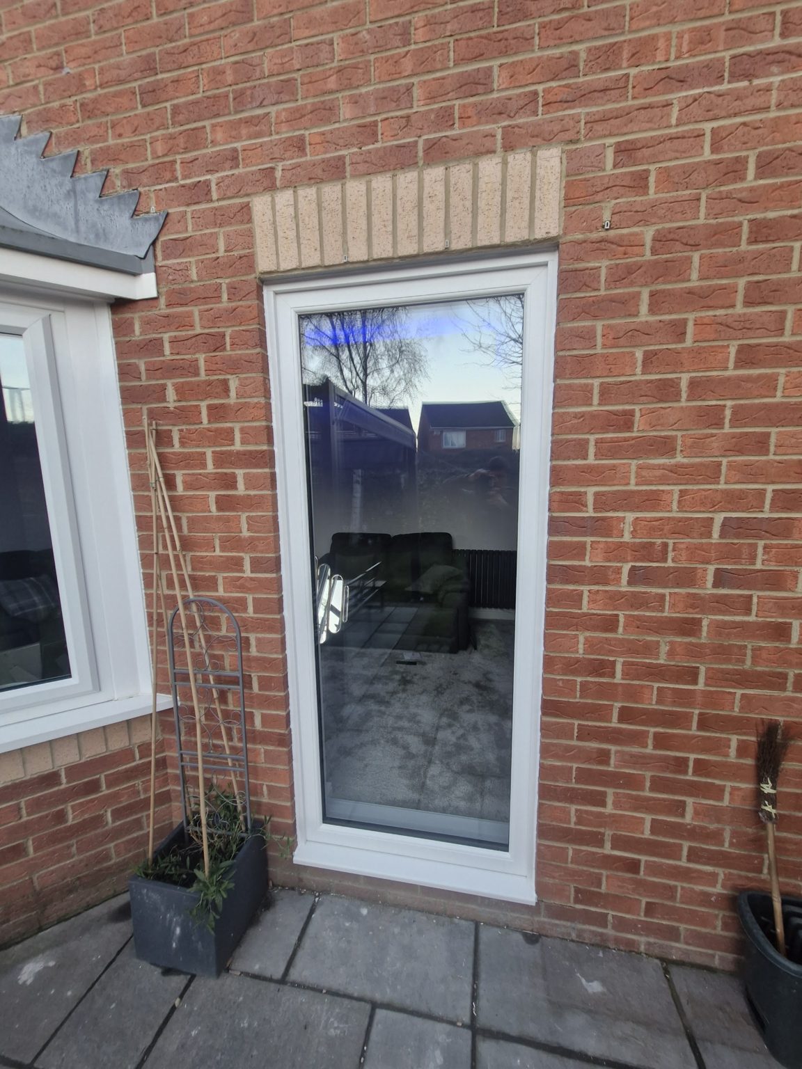 A full-height glazed white door fitted into a brick rear wall