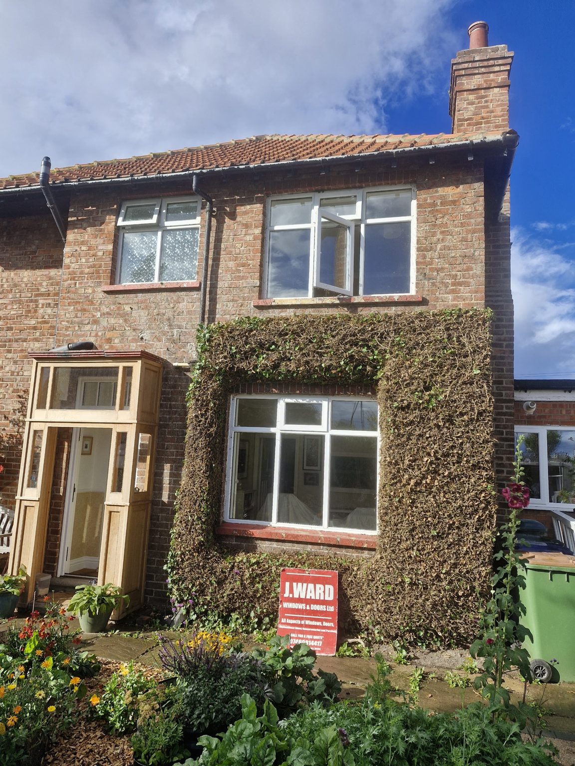A semi-detached house with new white windows and a porch, with the J.Ward board in the front garden