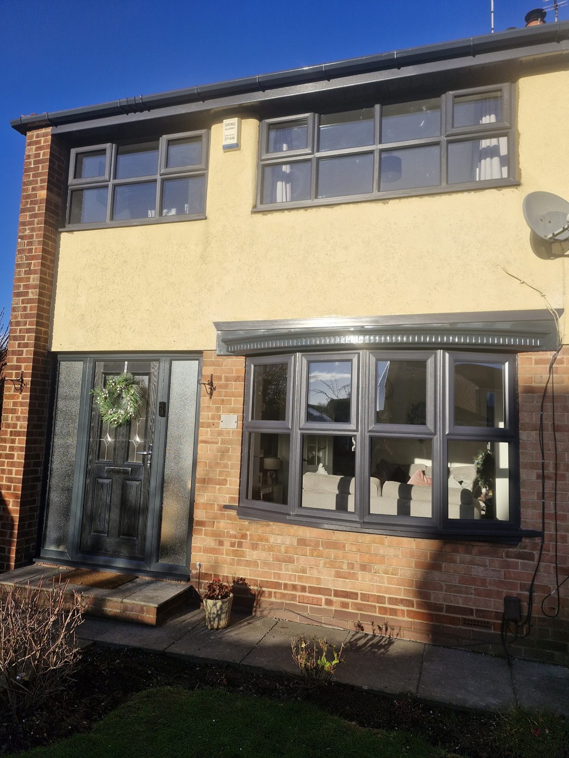 A rendered house with new grey windows and a box bay window