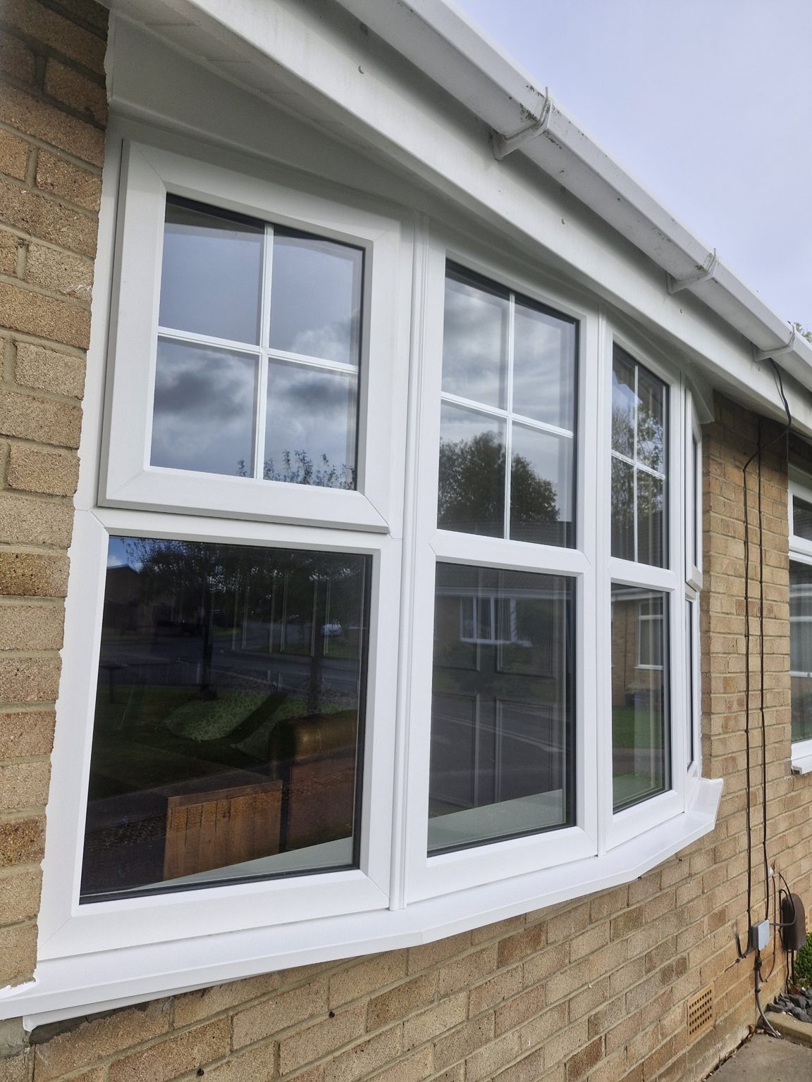 A close view of a new white bay window with barred top lights